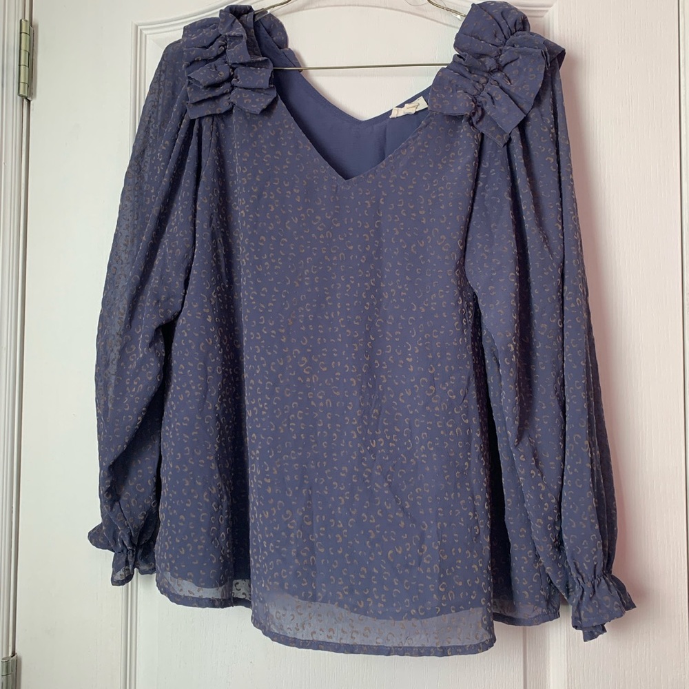 This is a blue blouse with tan colored leopard print all over the shirt.